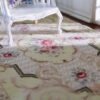 Light yellow Victorian miniature rug with floral medallion and scroll borders in beige and green.