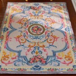 Pastel-colored miniature rug with floral accents and a central floral medallion design.