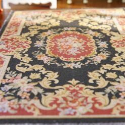 Red and black Aubusson style miniature rug with floral motifs and gold detailing
