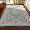 Miniature Victorian rug in soft blue featuring a central floral medallion surrounded by scrollwork.