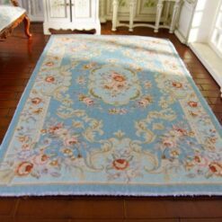 Miniature Victorian rug in soft blue featuring a central floral medallion surrounded by scrollwork.