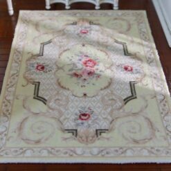 Light yellow Victorian miniature rug with floral medallion and scroll borders in beige and green.
