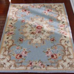 Blue miniature rug with vintage floral patterns in pink, cream, and green.