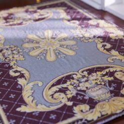 Burgundy miniature rug with yellow floral motifs, featuring a central floral medallion and ornate scrolls.