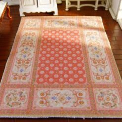 Miniature Aubusson rug in soft peach with floral accents and intricate scrollwork.