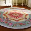 Miniature Victorian-style rug with a floral wreath and rose medallion design in soft colors.