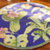 A miniature rug featuring colorful tropical flowers against a blue background with lush green leaves