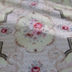 Light yellow Victorian miniature rug with floral medallion and scroll borders in beige and green.