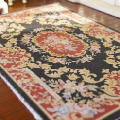 Red and black Aubusson style miniature rug with floral motifs and gold detailing