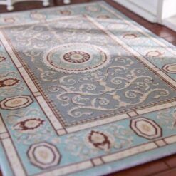 Soft blue and beige miniature rug with a floral medallion and intricate scrolling details.