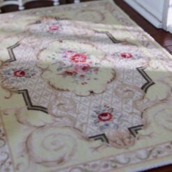 Light yellow Victorian miniature rug with floral medallion and scroll borders in beige and green.