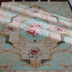 Light blue Victorian miniature rug with a floral medallion and scrolling vine patterns.