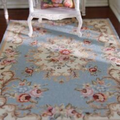 Blue miniature rug with vintage floral patterns in pink, cream, and green.