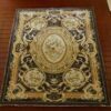 French Aubusson miniature rug with floral medallions and gold scroll designs on a dark brown background.