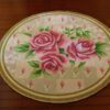 Round miniature rug with pink roses and rose buds on a soft background with a green border.