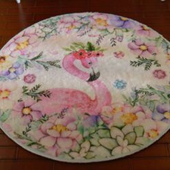 Miniature rug with a pink flamingo and pastel-colored flowers, including pink, purple, and blue hues.