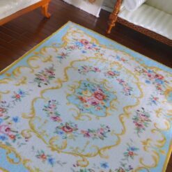 Victorian style miniature rug in pink and yellow with floral motifs and scroll borders