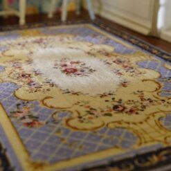 A yellow, blue and cream dollhouse miniature rug with an Aubusson-style medallion pattern and ornamental border.