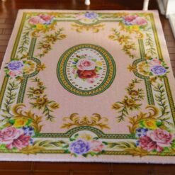 Light pink miniature rug with roses and floral scrolls, featuring a central medallion design.