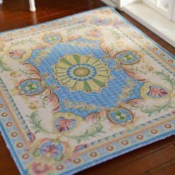 Pastel blue miniature rug with geometric medallions and floral accents, featuring symmetrical design elements.