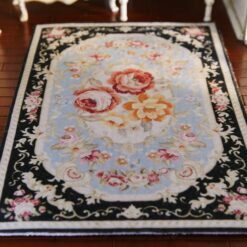 Persian-inspired miniature rug with a black background, floral bouquet center, and intricate floral border.