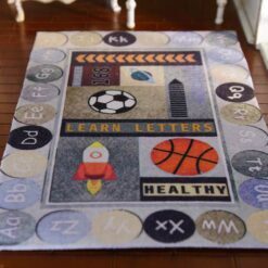 Miniature rug with an educational theme featuring letters, numbers, and playful images like a rocket and basketball.