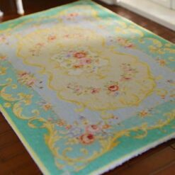 French Aubusson-style miniature rug with floral motifs and delicate scrollwork in blue and green hues.