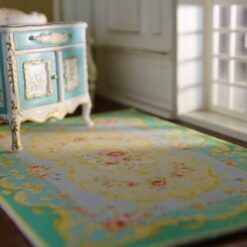French Aubusson-style miniature rug with floral motifs and delicate scrollwork in blue and green hues.