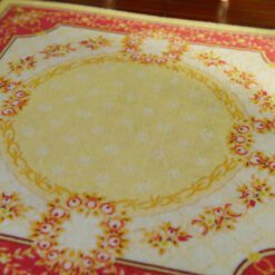 Miniature Aubusson square rug with floral border and yellow center.