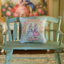 Miniature pillow design with two rabbits in blue and pink dresses surrounded by a rose wreath