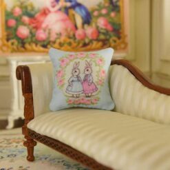 Miniature pillow design with two rabbits in blue and pink dresses surrounded by a rose wreath