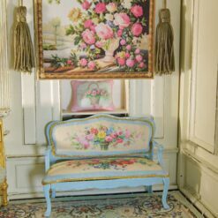 Ivory vase with colorful roses framed by a rich background, a miniature Aubusson tapestry.
