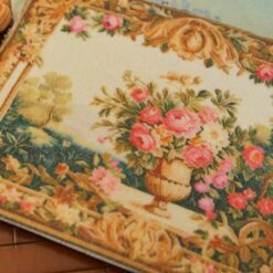 Miniature Aubusson tapestry featuring a golden urn with pastel roses framed by intricate scrollwork.