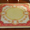 Miniature Aubusson square rug with floral border and yellow center.