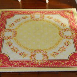 Miniature Aubusson square rug with floral border and yellow center.