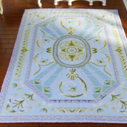 Light blue and green Aubusson rug with a central floral medallion and geometric patterns.