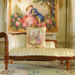 Miniature pillow with two rabbits in colorful outfits surrounded by pink roses