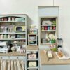 A double-sided corner cabinet kit for dollhouses, featuring open shelving and drawers.