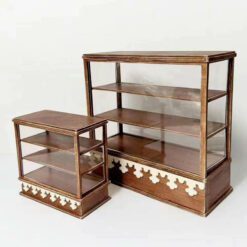 A vintage dollhouse bakery display cabinet with shelves and glass panels.