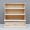 Unfinished wooden display cabinet with shelves and drawers for dollhouses.