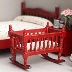 Miniature wooden rocking cradle for dollhouse nursery.