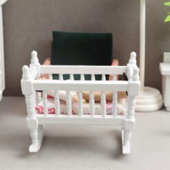 Miniature wooden rocking cradle for dollhouse nursery.