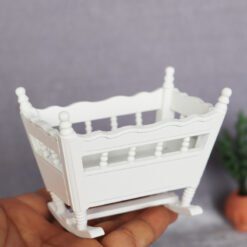 White miniature rocking cradle, ideal for nursery dollhouses.