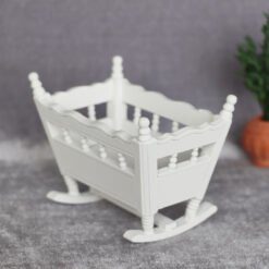 White miniature rocking cradle, ideal for nursery dollhouses.