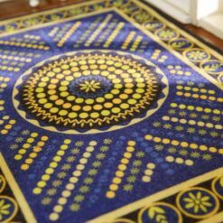 Geometric miniature rug with a spiral pattern of blue and yellow dots, bordered with floral accents.