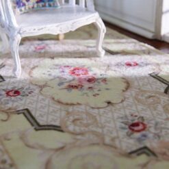 Light yellow Victorian miniature rug with floral medallion and scroll borders in beige and green.