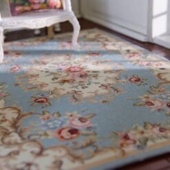 Blue miniature rug with vintage floral patterns in pink, cream, and green.