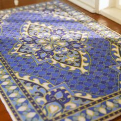 Persian miniature rug with a blue background, golden medallion, and intricate patterns.