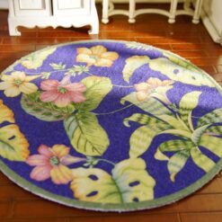 A miniature rug featuring colorful tropical flowers against a blue background with lush green leaves