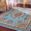 Miniature rug with a blue background and floral medallion, accented with scrollwork and floral details.